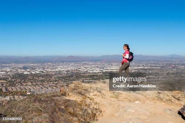 woman looking over the phoenix arizona skyline from a hiking trail on south mountain - phoenix skyline stock pictures, royalty-free photos & images