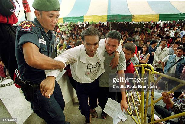 An AIDS patient too weak to walk is helped upstairs June 9, 2001 in Bangkok, Thailand. Thousands of AIDS patients came from all over Thailand waiting...