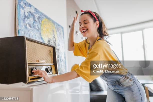 mujer divirtiéndose, cantando, bailando y escuchando música en casa - radio fotografías e imágenes de stock