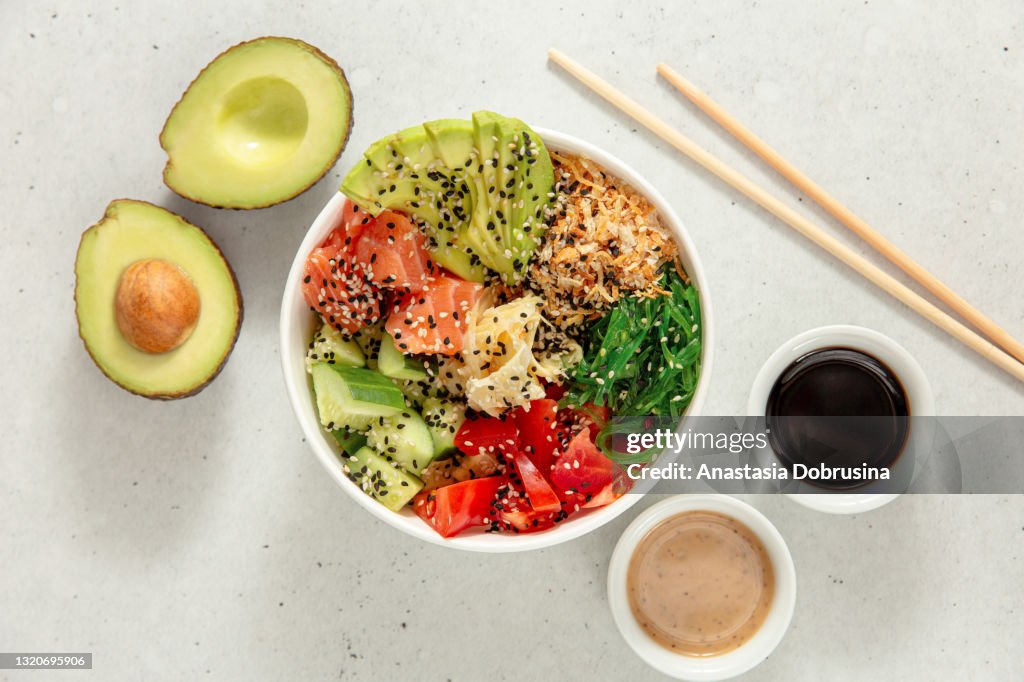 Poke bowl with salmon, avocado, cucumber, tomato and seaweed. Top view
