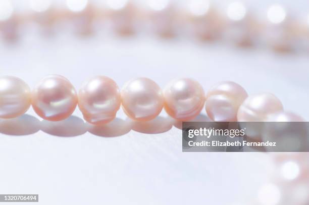 close-up of a string of pink pearls on silver background with copy space - fashion glamour pearl stock pictures, royalty-free photos & images