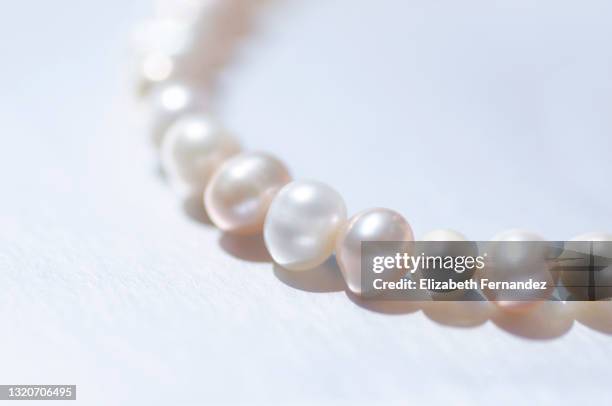 close-up of a string of pink pearls on silver background with copy space - pink pearls stockfoto's en -beelden