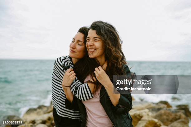 female friends enjoy walking the beach - female friendship stock pictures, royalty-free photos & images