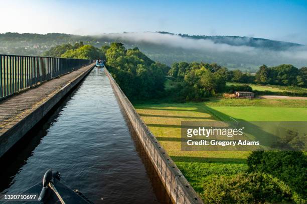 canal barging over an aqueduct on the llangollen canal in the united kingdom - kanaalsluis stockfoto's en -beelden