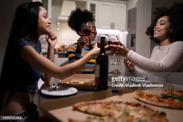 girlfriends eating pizza and drinking wine at home party - wine home delivery stock pictures, royalty-free photos & images