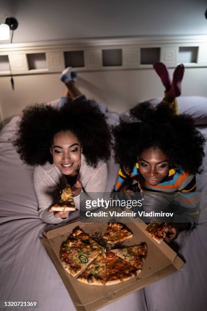 african women relaxing at home and eating pizza on bed - vertical tv stock pictures, royalty-free photos & images