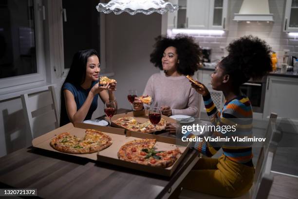 female multi-ethnic friends enjoying take out food pizza at home and drinking wine - wine home delivery stock pictures, royalty-free photos & images