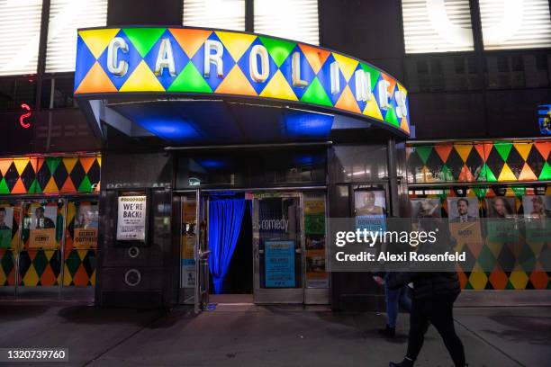 People walk past the newly reopened Caroline's Comedy Club in Times Square on Memorial Day weekend on May 29, 2021 in New York City. On May 19, 2021...