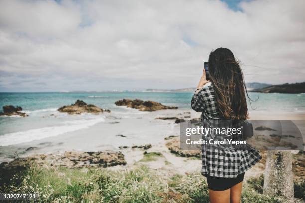 young hispanic woman taking pictures of wild atlantic beach in galicia,spain - call of the wild 個照片及圖片檔