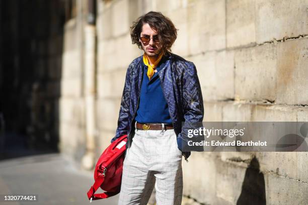 Alejandro Acero wears sunglasses, a yellow with white scarf, a blue polo Etro shirt, a blue with white and brown pattern zipper Etro jacket, a brown...