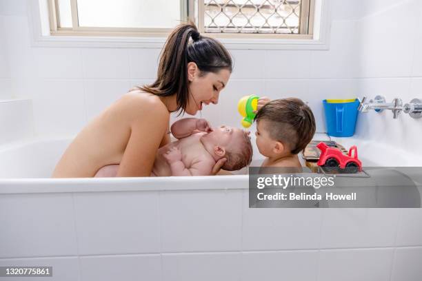 mother plays in the bath with her toddler and baby. - mother son shower stockfoto's en -beelden