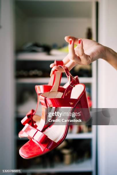 hands of a woman showing red sandals - hoher absatz stock-fotos und bilder