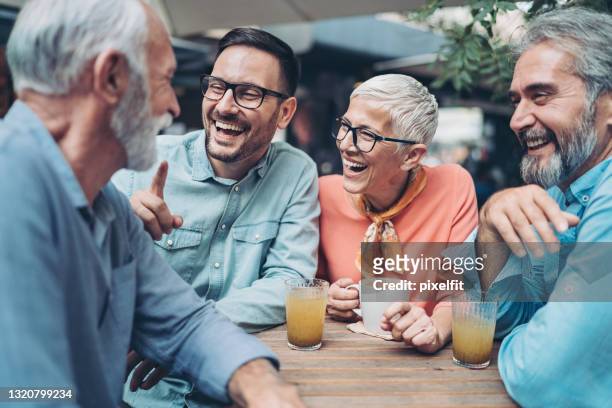 gruppe von freunden im café reden und lachen - gemischte altersgruppe stock-fotos und bilder