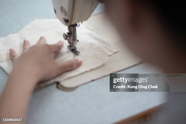 close up asian chinese female fashion college student sewing clothing using sewing machine at college workshop - sewing pattern stock pictures, royalty-free photos & images