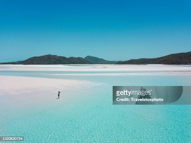 drone shot of a girl walking on whitehaven beach australia in crystal clear water - whitehaven beach stockfoto's en -beelden