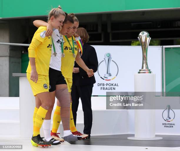 Merle Frohms and Alexandra Johannsdottir of Eintracht Frankfurt help injured team mate Tanja Pawollek on the podium as they receive their runners up...