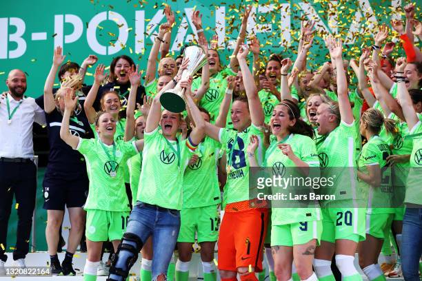 Alexandra Popp and Almuth Schult of VfL Wolfsburg lift the DFB Cup as their team mates celebrate victory in the Women's DFB Cup Final match between...