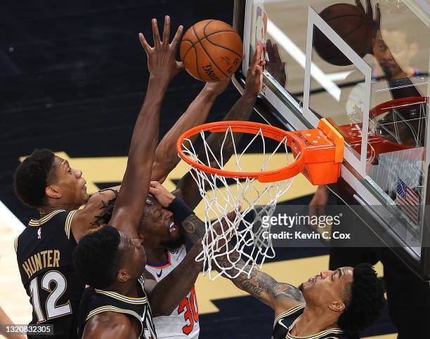 Julius Randle of the New York Knicks has the ball knocked away as he is defended by De'Andre Hunter, Clint Capela and John Collins of the Atlanta...