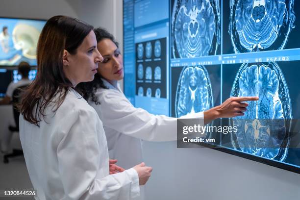 ärztin weist auf symptom bei mrt-scan an ihre kollegin hin. - scannen stock-fotos und bilder