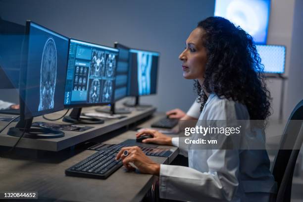 mujer hispana trabajando en computadora. doctora analizando el resultado de la exploración médica. - radiologist fotografías e imágenes de stock