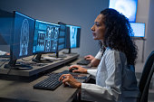 Hispanic woman working on computer. Female doctor analyzing medical scan result.