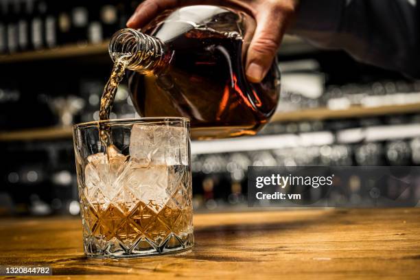 verser du verre de whisky. main masculine tenant bouteille avec de l’alcool de luxe. - whisky photos et images de collection