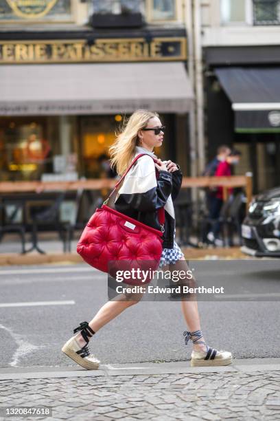 Almuneda Lapiquewears wears black sunglasses, a white with black inscriptions shirt with gold buttons, a silver white and black shiny leather Isabel...