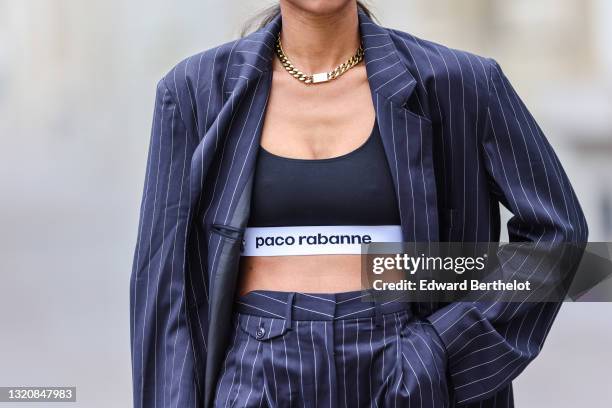 Emilie Joseph wears black sunglasses, golden earrings / earcuffs by Merbabe, a gold large chain necklace with thick cuban links by Merbabe, a black...