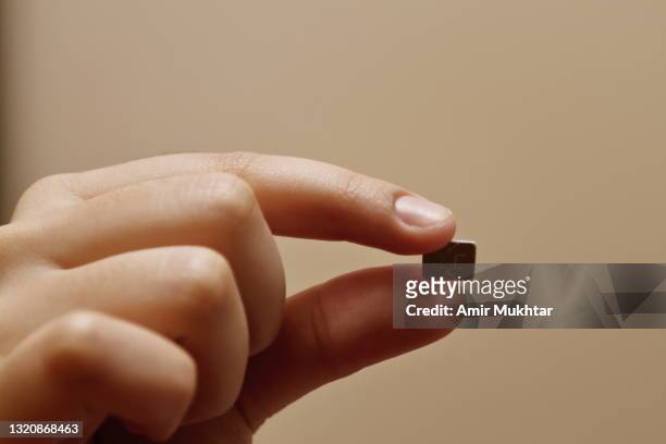 holding microchip in between thumb and index finger. - thumb stock pictures, royalty-free photos & images