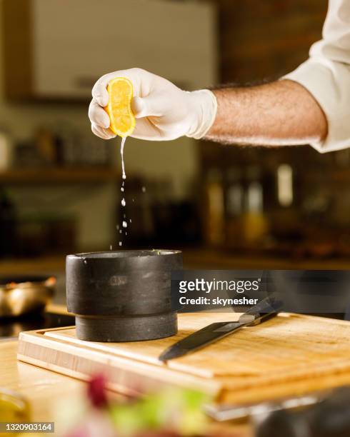 unrecognizable chef squeezing lemon juice into mortar and pestle. - lemon juice stock pictures, royalty-free photos & images