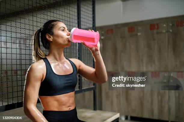 törstig kvinnlig idrottare dricker vatten på en paus i gymmets omklädningsrum. - backstage bildbanksfoton och bilder