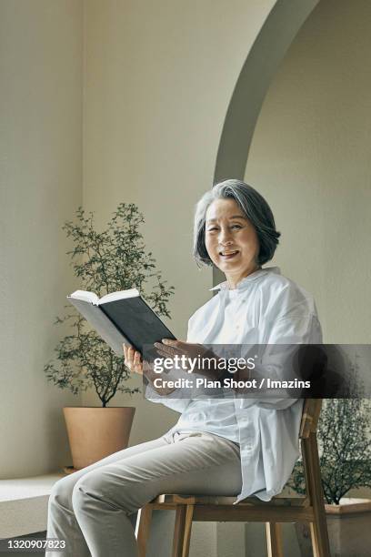 an old lady reading book near window - old book side stock pictures, royalty-free photos & images