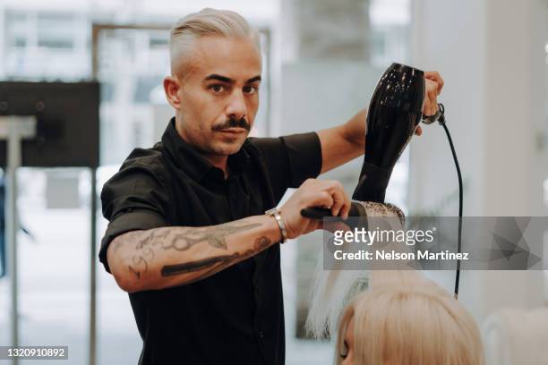 hairstylist serving client at hairdressing - föhn stock-fotos und bilder