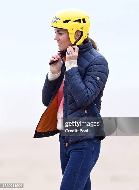 Catherine, Duchess of Cambridge puts on a crash helmet before taking part in a land yachting session on West Sands beach on May 26, 2021 in St...