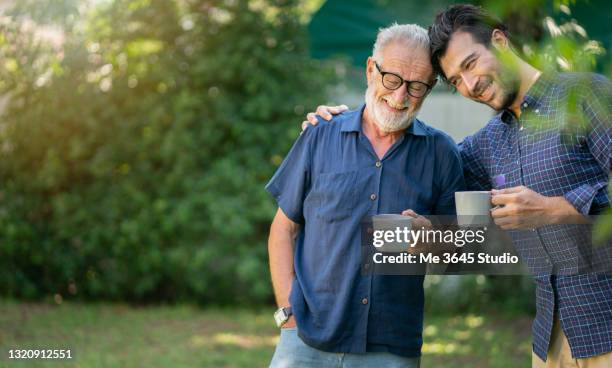 father and son holding a coffee cup . relationship father and son adult. - father and son gardening stock pictures, royalty-free photos & images