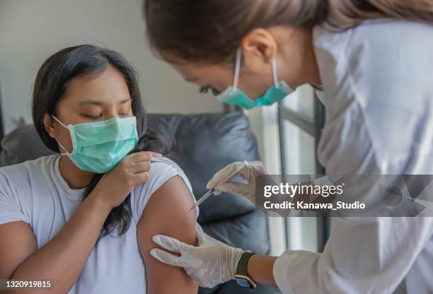aziatische gezondheidswerker die een patiënt het schot van vaccin geeft. - wereldwijde gezondheid stockfoto's en -beelden
