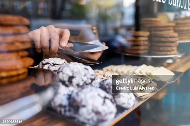 waiter picking up food from display for serving at a cafe - panetteria foto e immagini stock