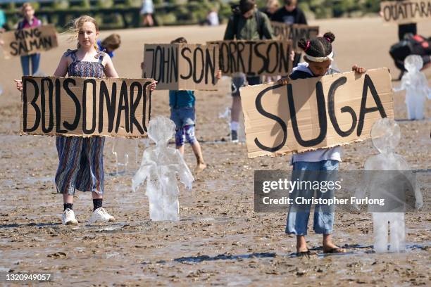 Children holding cardboard signs showing names of various world leaders, stand by some of 26 ice sculptures of children installed on New Brighton...