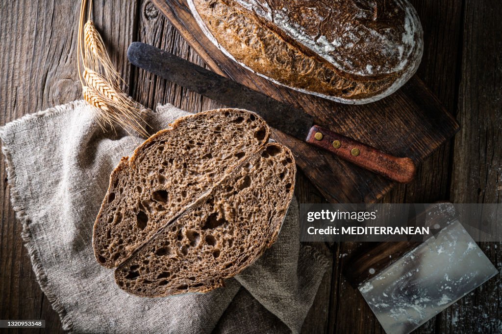 Het broodbrood van de zuurdesem en de mand van Banneton in bakkerij op houten rustieke lijst