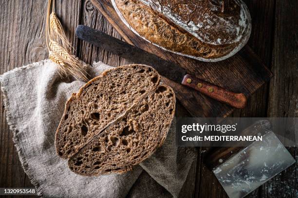 het broodbrood van de zuurdesem en de mand van banneton in bakkerij op houten rustieke lijst - roggebrood stockfoto's en -beelden