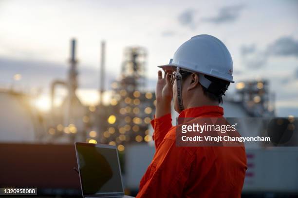 rear engineer with digital tablet and power plant background - industria petrolchimica foto e immagini stock