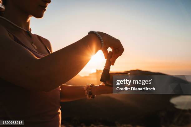 ung tjej gör meditation med en tibetansk sångskål under soluppgången i ett bergigt landskap och havslandskap - tibetansk kultur bildbanksfoton och bilder