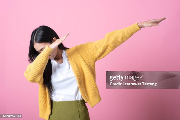young student woman 20s wearing  casual basic t-shirt doing dab hip hop dance hands move gesture youth sign hiding covering face isolated on dark pink color background studio portrait - dab dance stock pictures, royalty-free photos & images