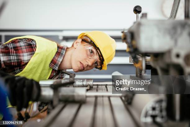 工場での掘削に取り組む保護具を持つ女性 - industrial machinery ストックフォトと画像