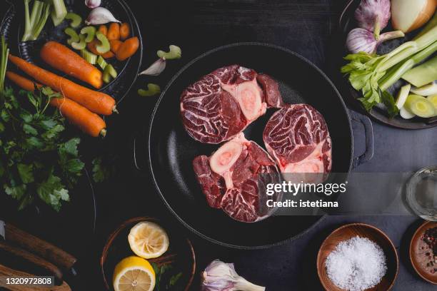 raw osso buco,  fresh veal cut meat in cast iron skillet, italian cuisine background with ingredients - osso bucco stock-fotos und bilder