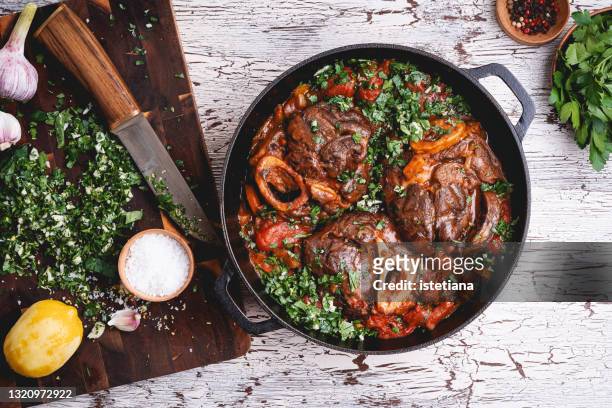 braised veal shank dish osso buco and gremolata green sauce - stew pot foto e immagini stock