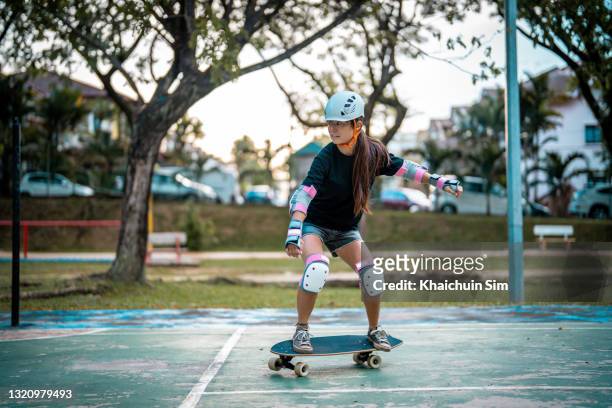 girl skateboarding in a park - playing badminton stock-fotos und bilder