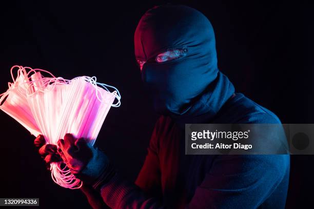 close-up of a thief that takes a bunch of  surgical masks in his hands. - coronavirus punishment stock pictures, royalty-free photos & images