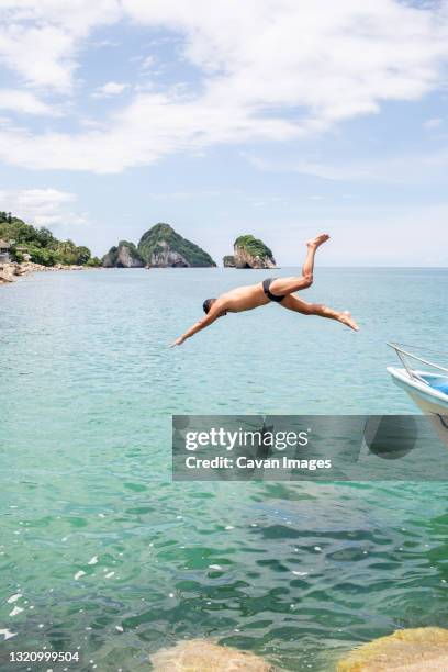 young fit man diving into ocean from front of boat - pacific fotografías e imágenes de stock