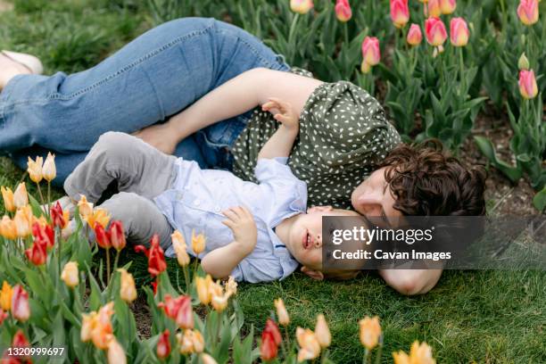 mom laying in the grass with toddler son in tulip garden - toddler marching stock pictures, royalty-free photos & images